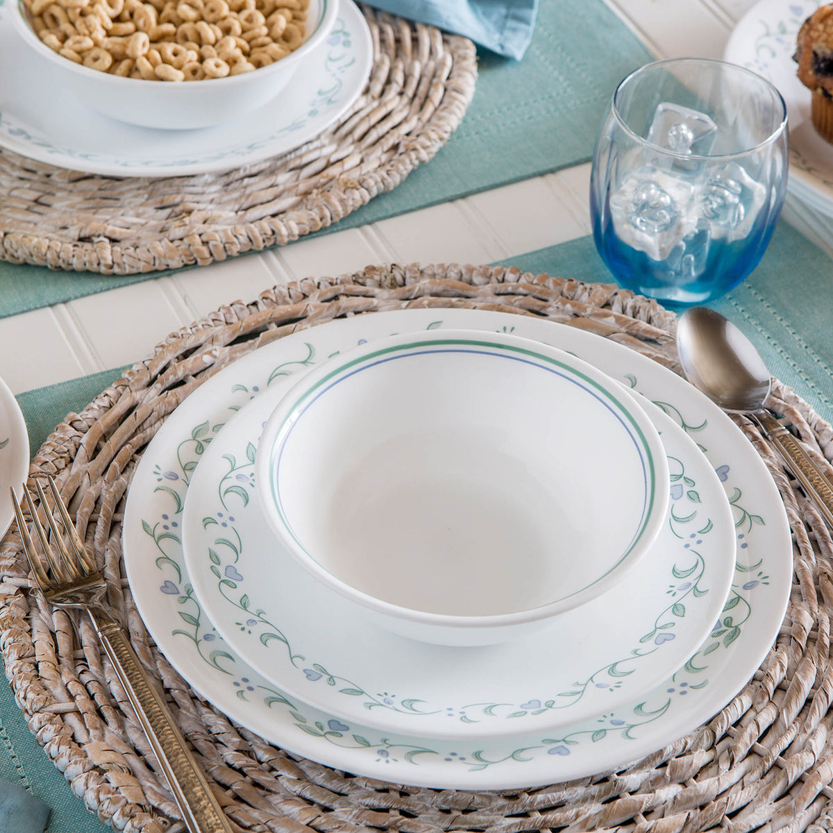 Corelle Country Cottage white dinnerware set with floral graphic design, showcasing plates and bowls in a charming, rustic style.