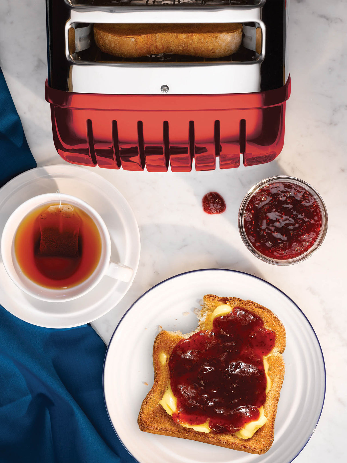 Roter DUALIT Toaster NEWGEN mit zwei Toastscheiben, modernes Design und praktische Bedienung, auf einem Küchenarbeitsplatz.