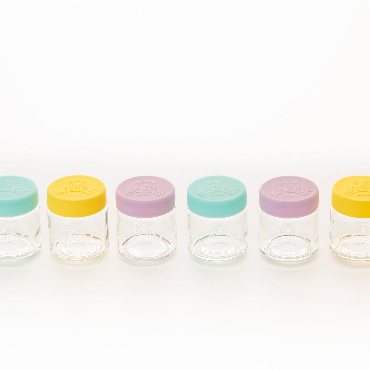 Bunte, klare Babygläser von KILNER mit bunten Deckeln, ideal für Baby-Nahrung und Aufbewahrung, auf weißem Hintergrund.