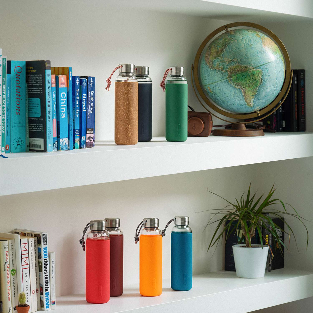 Schwarz-orange Glas-Wasserflasche von black+blum, 600 ml, mit transparentem Glas und orangefarbenem Deckel auf weißem Hintergrund.