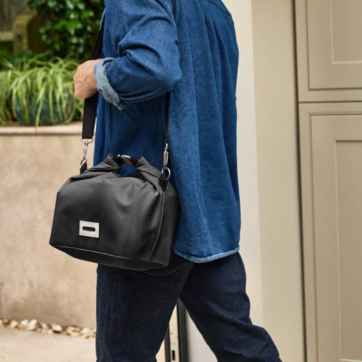 Schwarze isolierte Lunchbag von BLACK+BLUM mit Schultergurt, ideal für Lunch unterwegs, horizontale Ansicht.