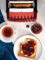 Roter DUALIT Toaster NEWGEN mit zwei Toastscheiben, modernes Design und praktische Bedienung, auf einem Küchenarbeitsplatz.