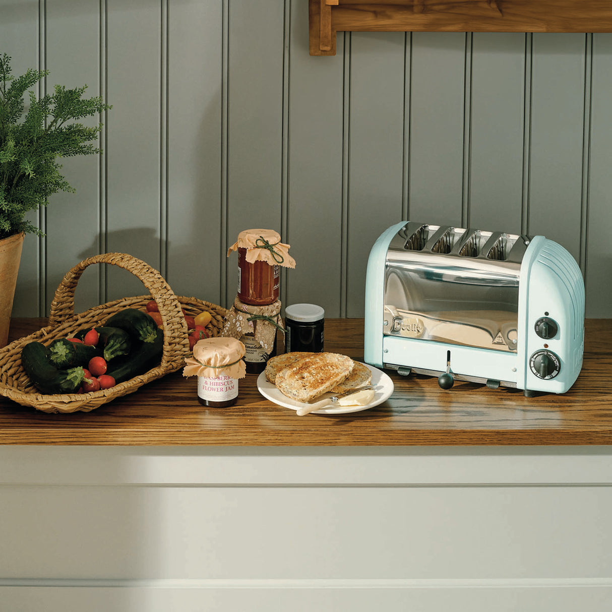 Heller blauer DUALIT Toaster NEWGEN mit 4 Scheiben, modernes Design und Edelstahl-Details, auf einer Küchenarbeitsplatte.