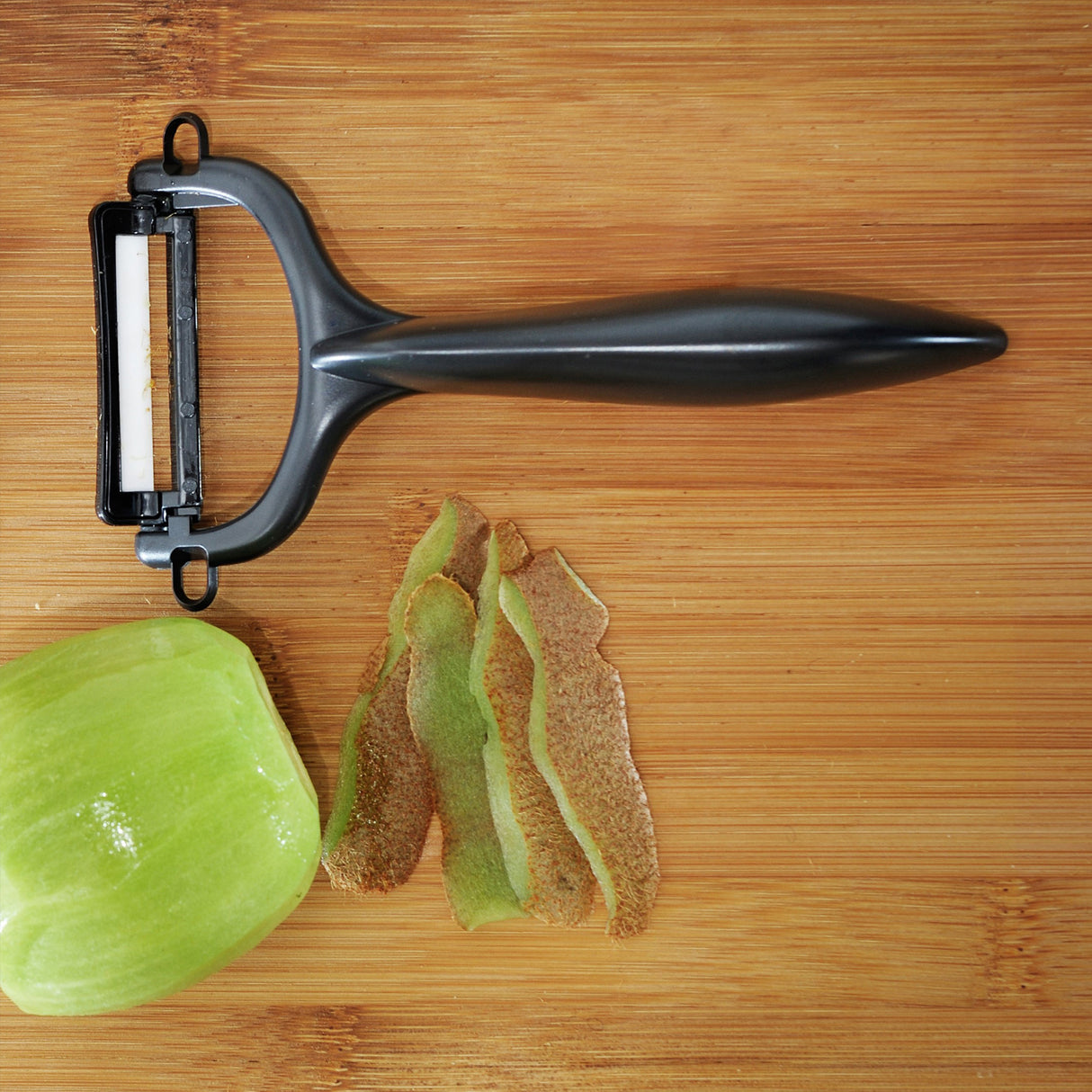 Grüner KYOCERA Schäler mit doppelseitigem Schliff, handliches Küchenwerkzeug für Gemüse und Obst.