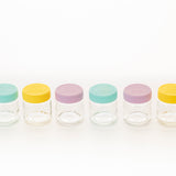 Bunte, klare Babygläser von KILNER mit bunten Deckeln, ideal für Baby-Nahrung und Aufbewahrung, auf weißem Hintergrund.