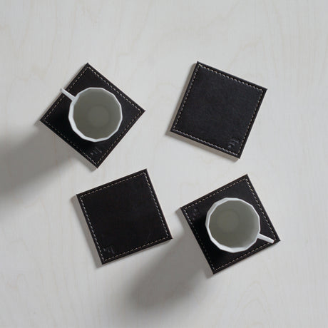 Vier graue und schwarze Untersetzer im Freeform DUO 4er Set aus robustem Material, ideal für Tische und Möbel.