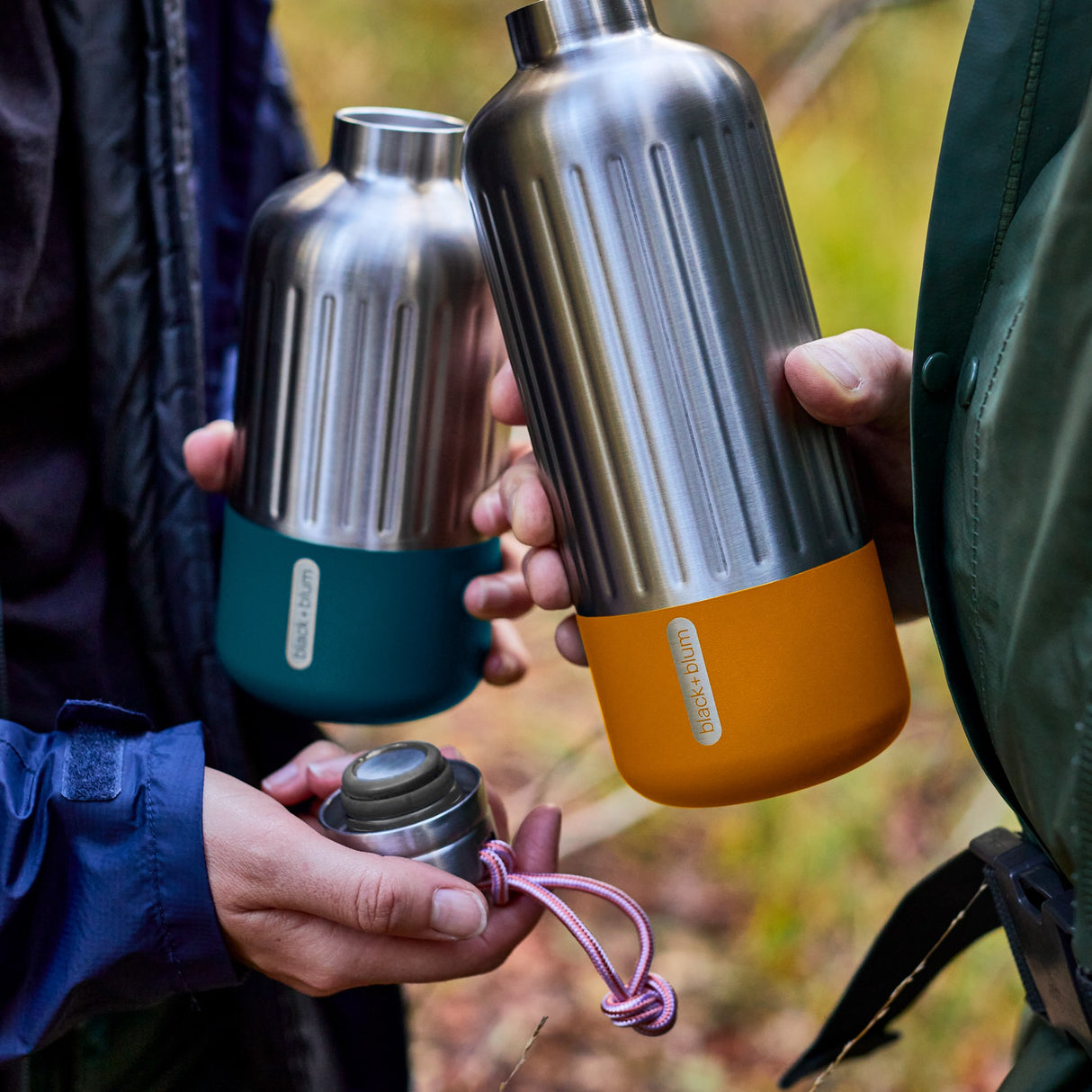 BLACK+BLUM Isolierflasche Explorer in Orange, langlebig und ideal für Outdoor-Aktivitäten, zeigt die Flasche im Lifestyle beim Wandern.