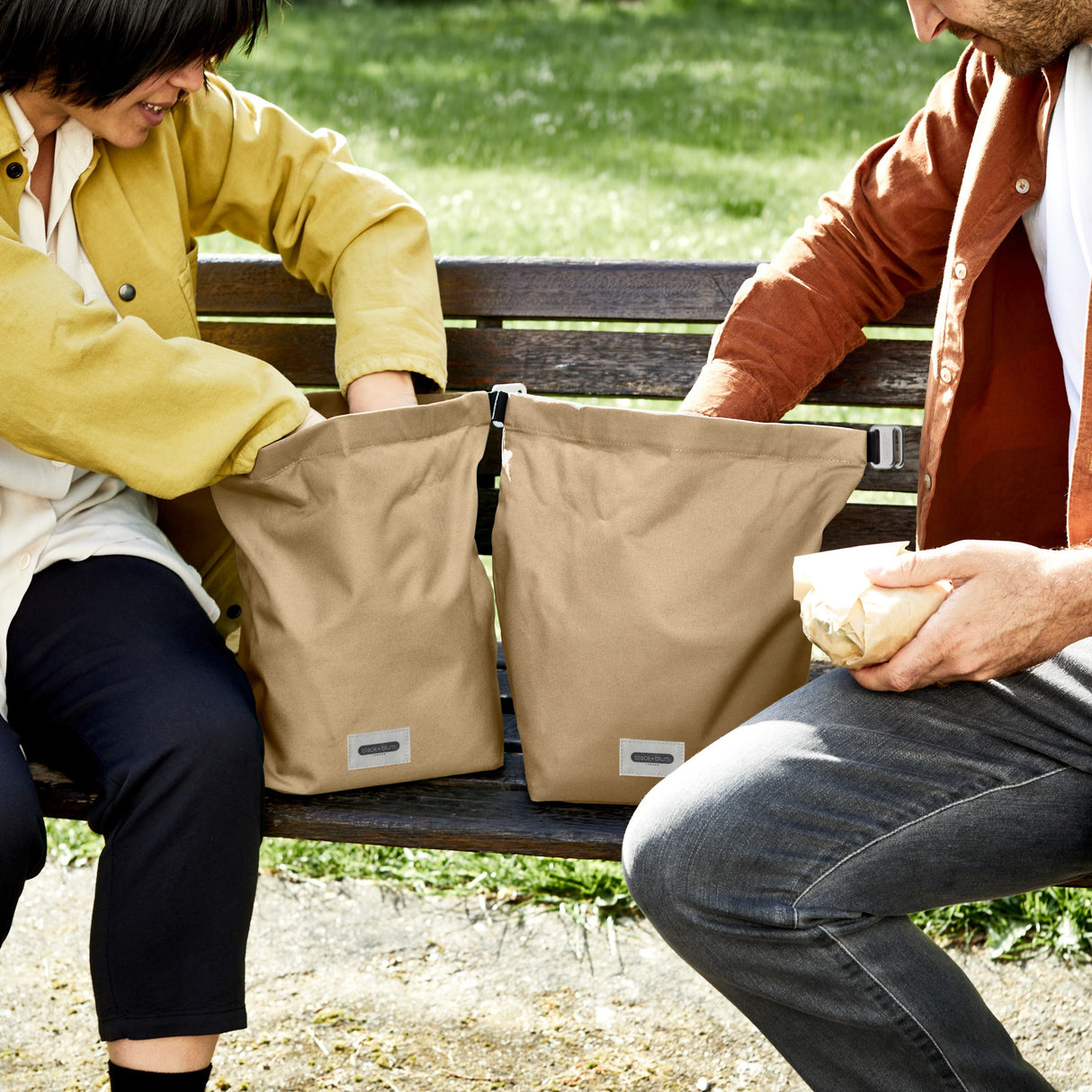 Schwarze BLACK+BLUM Lunchbag mit 6,7 Litern Fassungsvermögen, geöffnet im Park, zeigt Innenraum und robustes Design.
