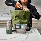 Schwarzer BLACK+BLUM Lunchbag, isoliert, offen auf einem Tisch mit Essen, für Lunch und unterwegs.