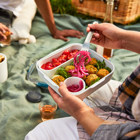 Schwarze BLACK+BLUM Lunchbox mit Falafel und Salat, original, aus robustem Material, ideal für unterwegs und Lunches.